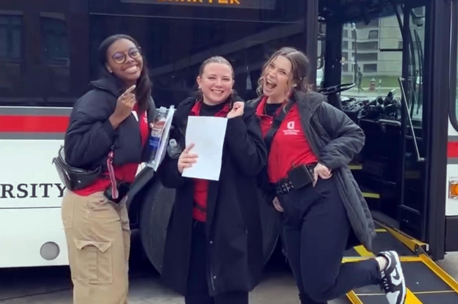 Hosts posing for a photo outside a cabs bus